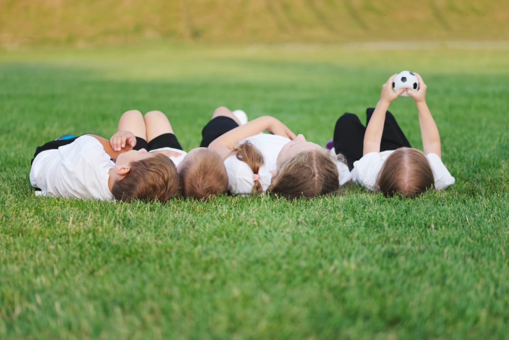 happy children lying on football pitch