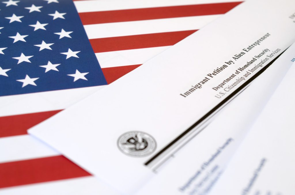 I-526 Immigrant Petition by Alien Entrepreneur blank form lies on United States flag with envelope